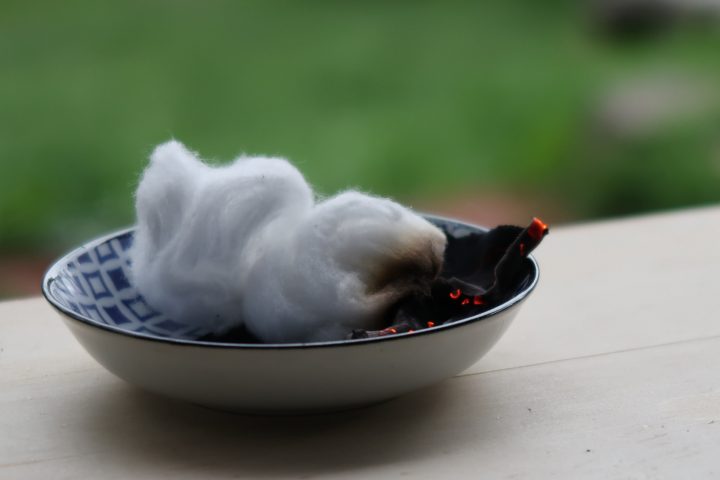 a small blue dish containing cotton wool balls next to some smouldering char cloth