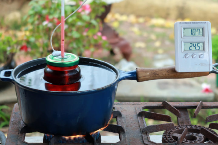 a saucepan of water on a camping stove warms a diy thermometer for temperature calibration