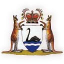 A shield has a black swan floating on a blue base. It is supported by two red kangaroos each holding a boomerang. Atop is a crest with a royal crown flanked by kangaroo paw flowers. The crest sits on a black and gold wreath.